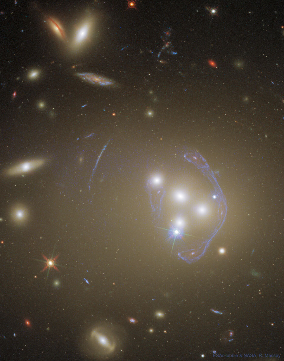 The picture shows galaxy cluster Abell 3827 from Hubble. Cluster
galaxies are seen merging and a complex image of a background galaxy 
is seen where the cluster acts as a gravitational lens. 
Please see the explanation for more detailed information.