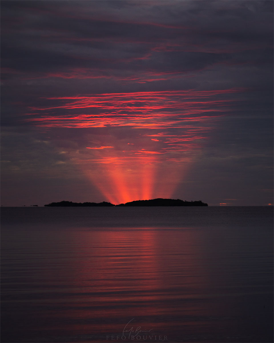 The featured image shows crepuscular rays emanating 
from below the horizon and appearing quite red. 
Please see the explanation for more detailed information.