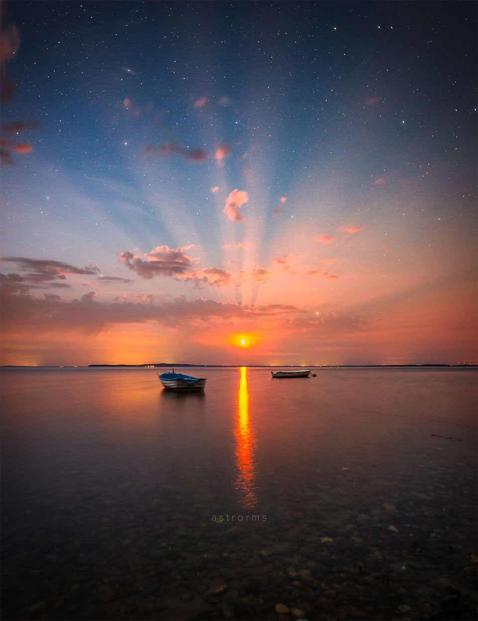 The featured image shows the Moon rising over water surrounded by
bright rays that peek through clouds. 
Please see the explanation for more detailed information.