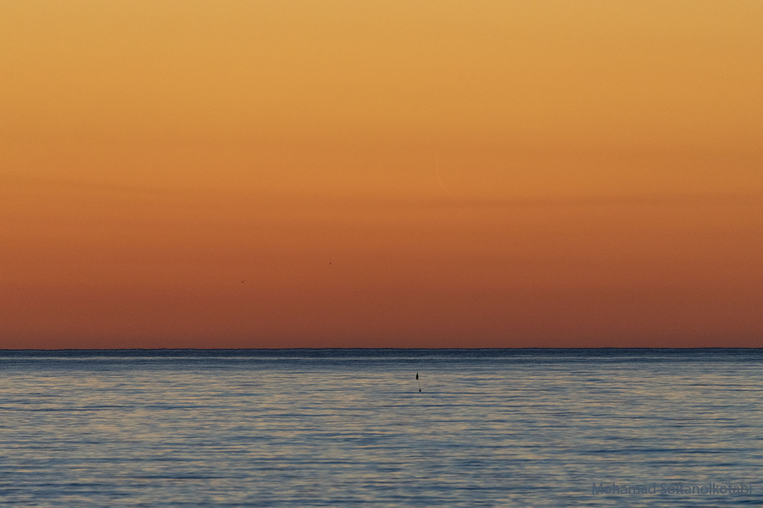 The featured image shows an orange sky over water with 
a very faint, slight crescent Moon in the sky. 
Please see the explanation for more detailed information.