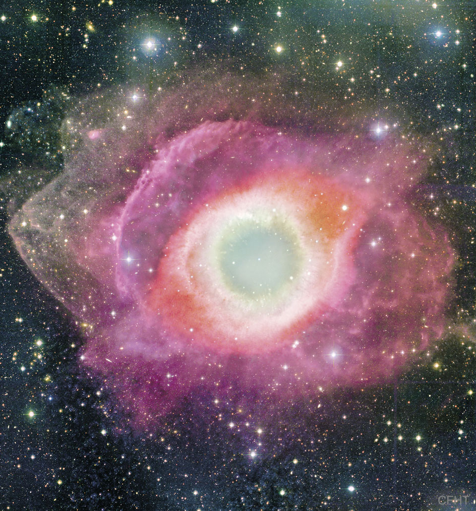 A colorful circular nebula is shown that is beige in the center,
red further out, and gas violet rings even further out.
Please see the explanation for more detailed information.