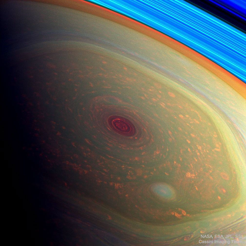 Saturn's north pole is shown with vibrant false colors. 
The outer boundary appears as a rounded hexagon. 
Please see the explanation for more detailed information.