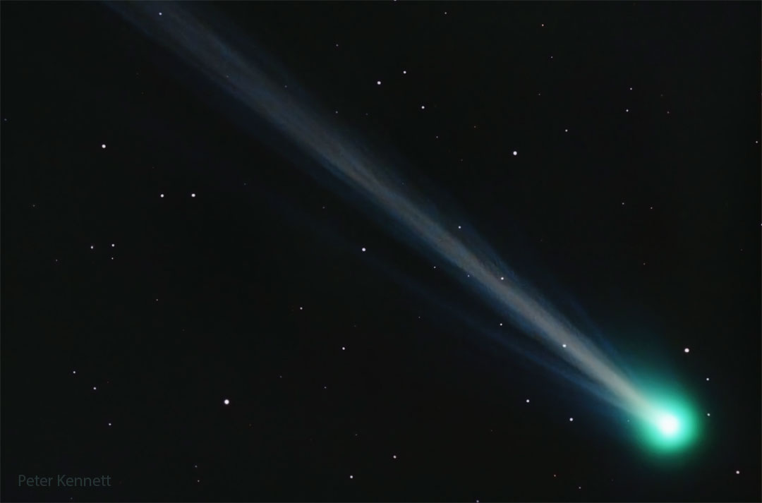 A comet is shown with its green coma on the bottom right
and a long and structured ion tail flowing diagonally across 
the image toward the top left.
Please see the explanation for more detailed information.