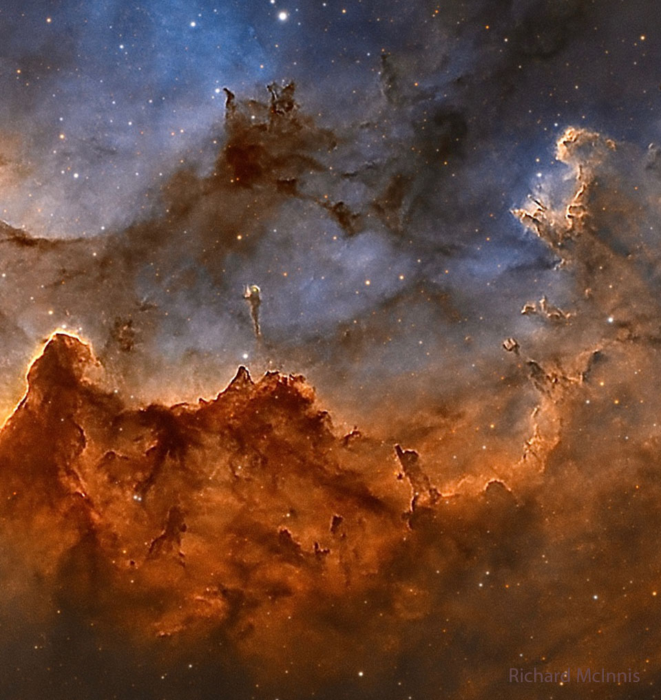 The center of the Wizard Nebula is shown featuring 
gas glowing in red and dust reflecting in blue. Dark
dust pillars are seen throughout the image. 
Please see the explanation for more detailed information.