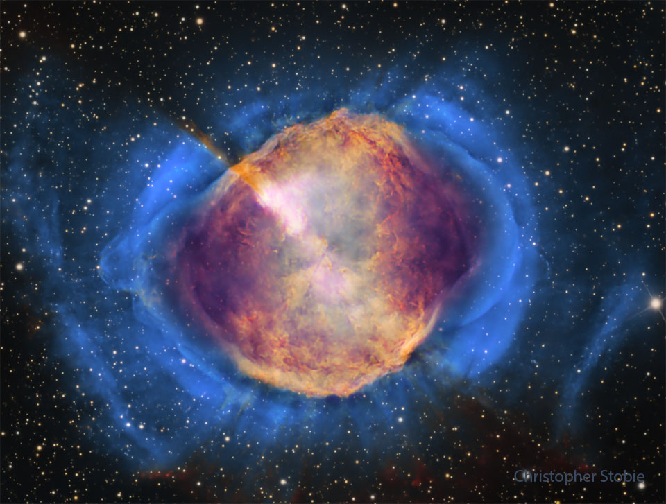 A starfield is shown with a frame dominated by a gaseous
nebula. The nebula, filled with structure, appears orange 
in the center but blue
around the edges. 
Please see the explanation for more detailed information.