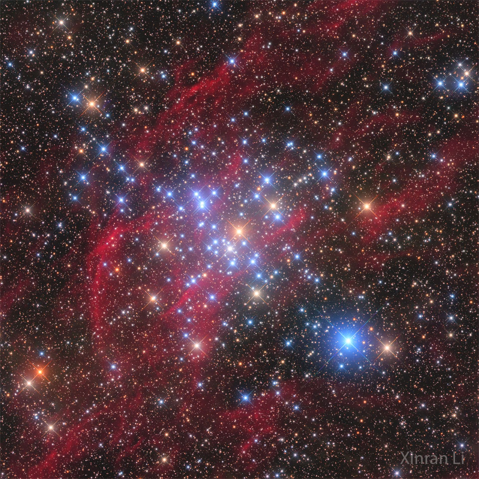 A starscape is shown with red filaments running 
diagonally from the lower left to the upper right.
Many bright blue stars are visible across the center
of the frame. 
Please see the explanation for more detailed information.