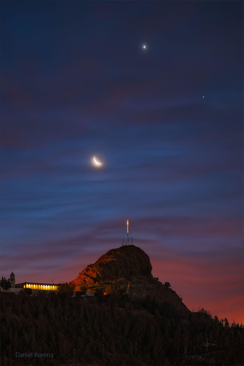 The featured image shows a night sky over a distant hill.
The night sky has three bright objects: a crescent moon, the planet
Venus (highest), and the planet Saturn. Taken together, the moon
and planets make a happy face icon. 
Please see the explanation for more detailed information.