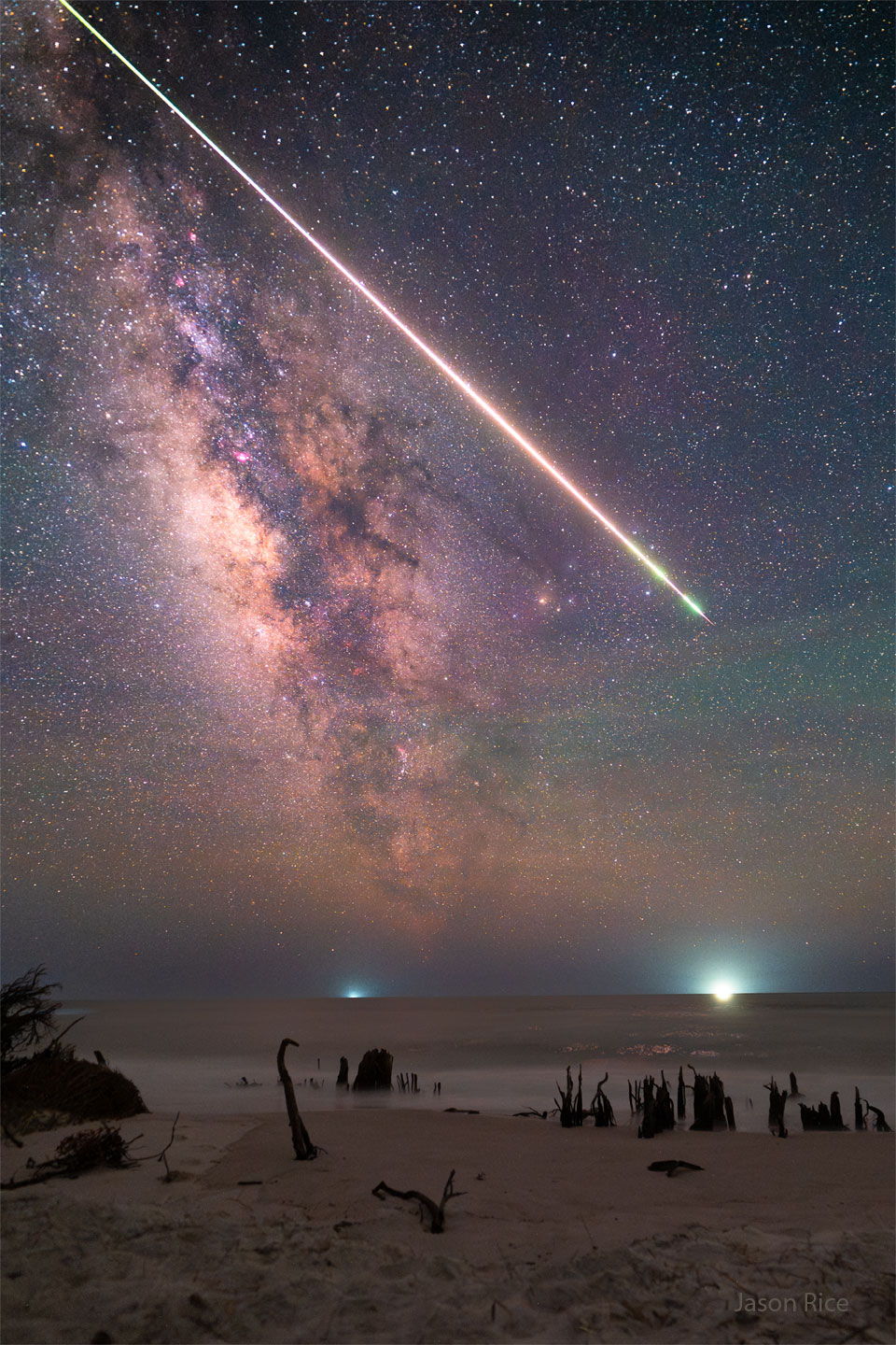 A bright streak is pictured through a starry sky over a 
beach spotted with the husks of dead trees. The rollover
shows the resulting smoke trail from the bright meteor.
Moving the cursor over the image will bring up an annotated version.
Clicking on the image will bring up the highest resolution version
available.
Please see the explanation for more detailed information.
