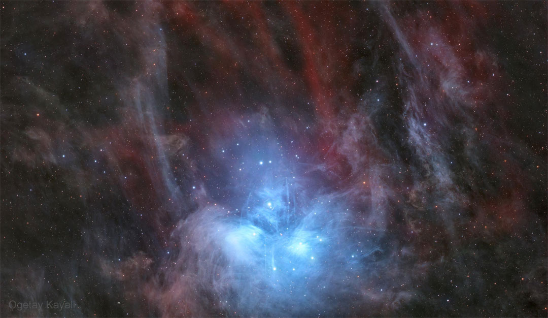 A cluster of bright blue stars is seen near the bottom
of this starfield. Nebula around the stars is blue near
the stars but red elsewhere. 
Please see the explanation for more detailed information.