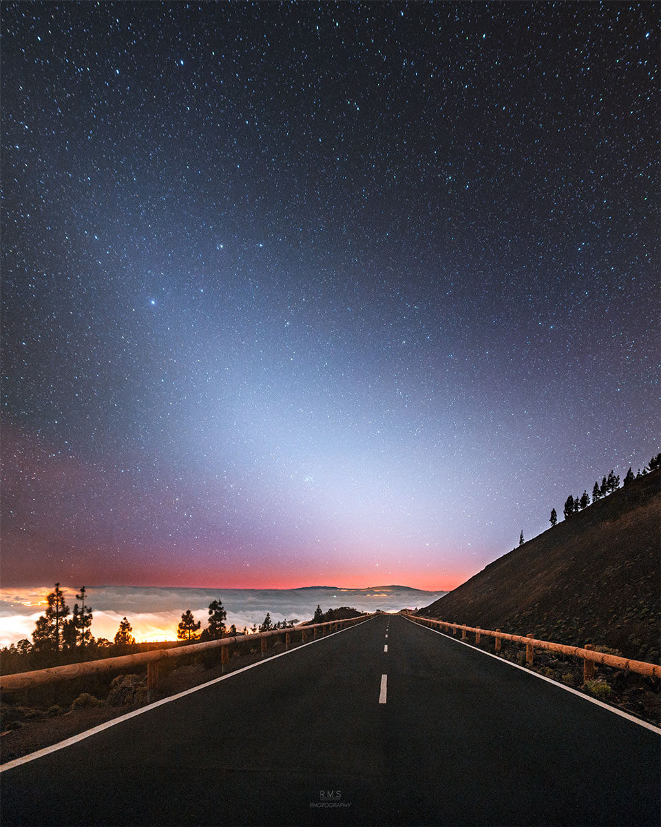 A night sky is shown above a road going off into
the distance. An unusual area of brightened sky that 
does not block background stars appears diagonally
from the lower right across the sky.
Please see the explanation for more detailed information.