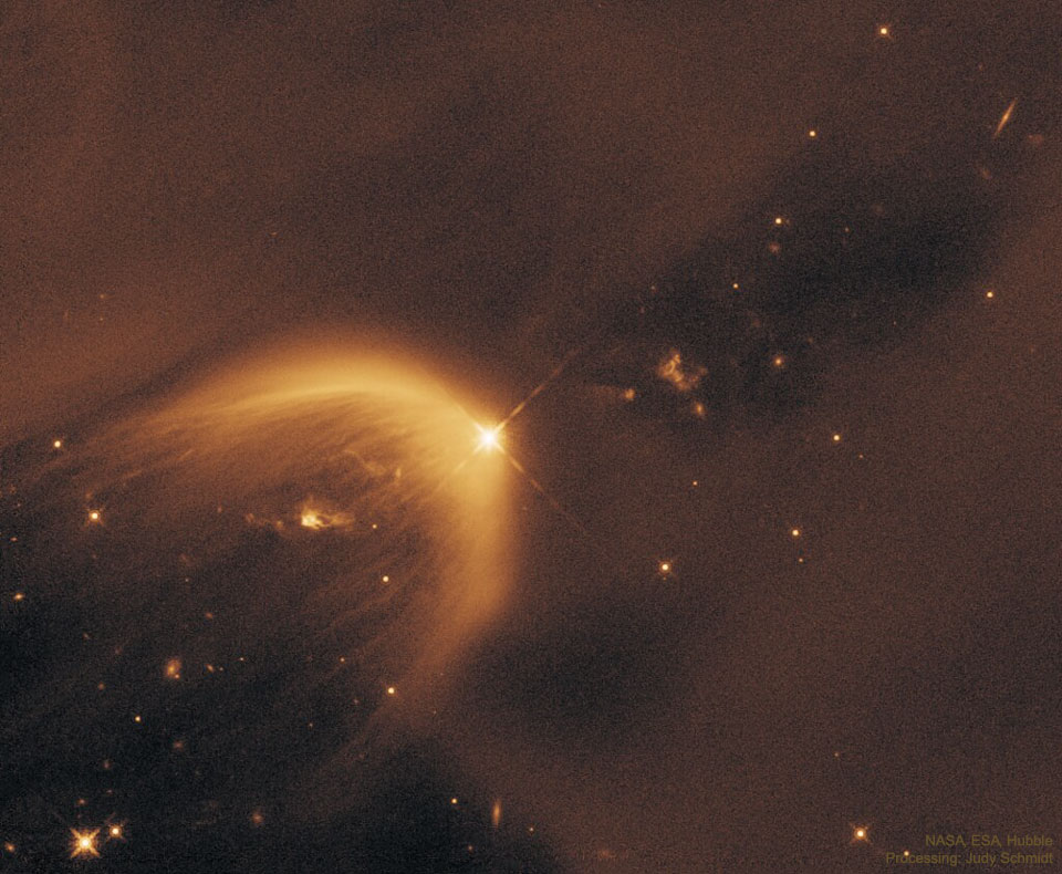 A starfield is dominated by light brown dust. In the 
middle is a parabolic gas cloud opening toward the lower right.
A bright star is near the center at the apex of the parabolic
gas cloud. 
Please see the explanation for more detailed information.