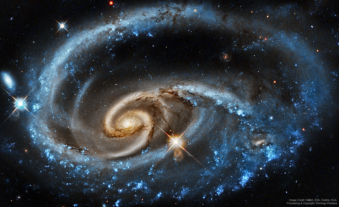 A bright galaxy with unusual blue spiral arms is shown
against a dark starfield. The outer part of the spiral 
appears as a blue ring, while the inner part appears to
have separate -- and more tan -- spiral structure. 
Please see the explanation for more detailed information.