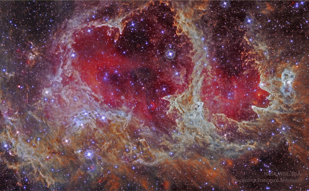 A star field is shown in infrared light. In the center
is an extremely complex nebula that is outlines an iconic
heart. Glowing gas shades the center of the heart red.
Please see the explanation for more detailed information.